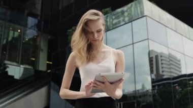 Beyaz tişörtlü bir iş kadını portresi arkasında iş merkezi olan bir tablet bilgisayar kullanıyor. İş kadını iş ortağıyla buluşuyor, iş ortağı bekliyor ve elinde bir tablet tutuyor..