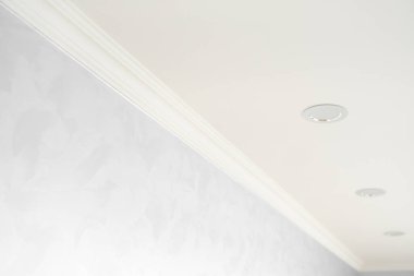 Gri boyalı duvarları olan bir odada beyaz bir kaide. Tavanla odadaki duvar arasındaki köşenin dekorasyonu. Tavan döşemesi iç kısımda. Köşenin ayrıntıları.