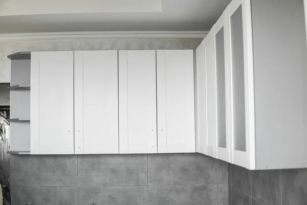 Custom kitchen cabinets installation with a white furniture facades mdf. Gray modular kitchen from chipboard material on a various stages of installation. A frame furniture fronts mdf profile. — Stock Photo, Image