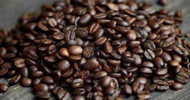 Ahşap bir masaya saçılmış kavrulmuş Arap kahve çekirdekleri. Taze kahve çekirdekleri. Espresso, americano, doppio, cappuccino, latte. Robusta. Seçici odak.