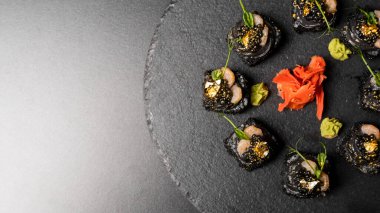 Suşi, siyah pirinç, yengeç eti, salatalık, avokado, tütsülenmiş somon balığı, kürek havyarı, masago, karides kokteyli ve kırmızı zencefil ve wasabi soslu yenilebilir altın yaprak..