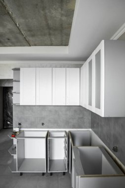 Beyaz mobilya cepheli özel mutfak dolapları kurulumu. Gri modüler mutfak, çeşitli kurulum aşamalarındaki çip malzemelerinden. Bir çerçeve mobilya MDF profilinin önünde.