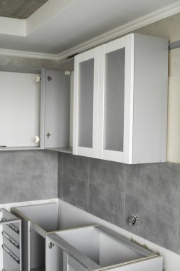 Beyaz mobilya cepheli özel mutfak dolapları kurulumu. Gri modüler mutfak, çeşitli kurulum aşamalarındaki çip malzemelerinden. Bir çerçeve mobilya MDF profilinin önünde.