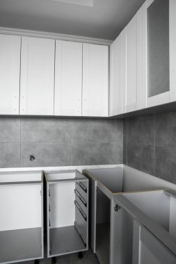 Beyaz mobilya cepheli özel mutfak dolapları kurulumu. Gri modüler mutfak, çeşitli kurulum aşamalarındaki çip malzemelerinden. Bir çerçeve mobilya MDF profilinin önünde.
