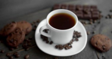 Kurabiyeli kahve, çikolata ve ahşap masaya saçılmış kahve çekirdekleri. Sade kahve kupası. Taze Arap usulü kavrulmuş kahve çekirdekleri. Harika bir sabah başlangıcı. Espresso, americano, doppio.