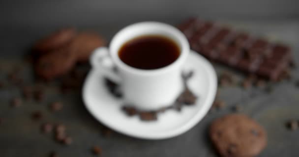 Kopje koffie met koekjes, chocolade en gebrande koffiebonen verspreid over een houten tafel. Zwarte koffiemok. Verse arabica gebrande koffiebonen. Goed begin van de ochtend. Espresso, americano, doppio. — Stockvideo