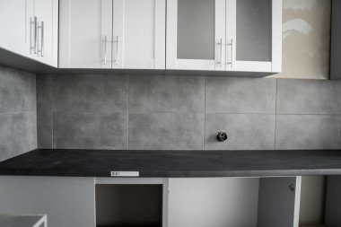 Beyaz mobilya cepheli özel mutfak dolapları kurulumu. Gri modüler mutfak, çeşitli kurulum aşamalarındaki çip malzemelerinden. Bir çerçeve mobilya MDF profilinin önünde.