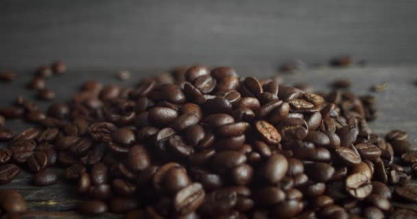 Biji kopi arabika panggang tersebar di atas meja kayu. Biji kopi segar. Espresso, americano, doppio, cappuccino, latte. Robusta. Fokus selektif. — Stok Video