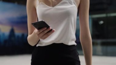 Beyaz tişörtlü genç iş kadını gülüyor ve telefonda iş ortaklarıyla konuşuyor ya da iş merkezi ya da alışveriş merkezi arkasında arkadaşlarıyla. Mutlu kız komik bir şey söyler ya da duyar..