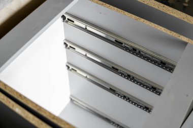 Paslanmaz teleskopik süngü çekmecesi kaydırak rehberleri, gri yonga masasından mutfak dolabına monte edilmiş. Mobilya yapımında kullanılan marangozluk aksesuarları. Özel mutfak kurulumu.