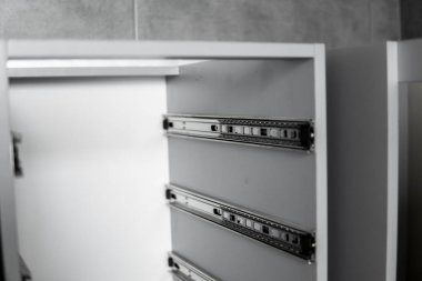 Paslanmaz teleskopik süngü çekmecesi kaydırak rehberleri, gri yonga masasından mutfak dolabına monte edilmiş. Mobilya yapımında kullanılan marangozluk aksesuarları. Özel mutfak kurulumu.