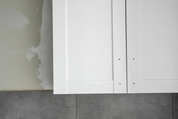 Инсталляция кухонных шкафов на заказ с белым мебельным фасадом mdf. Серый модульная кухня из ДСП материала на различных этапах установки. Мебель для рамы фасадов mdf профиля. — стоковое фото