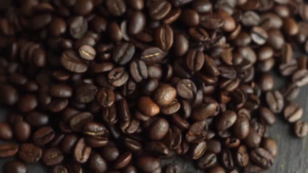 Grains de café arabica torréfiés éparpillés sur une table en bois. Des grains de café frais. Espresso, americano, doppio, cappuccino, latte. Robusta. Concentration sélective. — Video