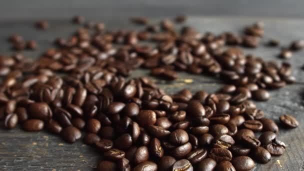 Grãos de café arábica torrados espalhados em uma mesa de madeira. Grãos de café frescos. Espresso, americano, doppio, cappuccino, latte. Robusta. Foco seletivo. — Vídeo de Stock