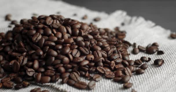 Geröstete Kaffeebohnen verstreut auf einem Leinenstoff auf einem Holztisch. Frisch geröstete Arabica-Kaffeebohnen Espresso, American, Doppelio, Cappuccino, Latte. Robusta. Selektiver Fokus. — Stockvideo