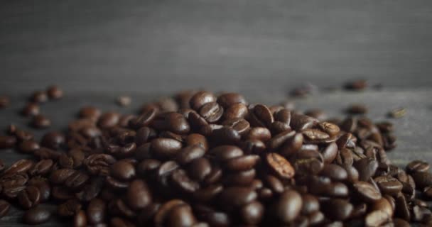 Pražená arabská kávová zrna roztroušená na dřevěném stole. Čerstvá kávová zrna. Espresso, americano, doppio, cappuccino, latte. Robusto. Selektivní zaměření.