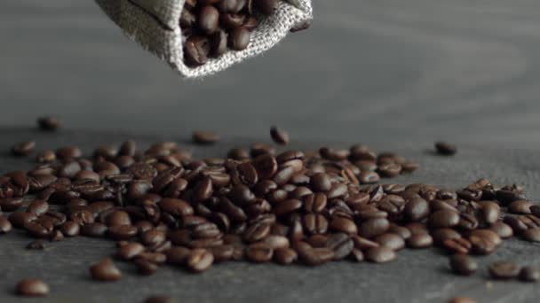 手は木製のテーブルのリネン袋からコーヒー豆を散布します。アラビカ豆の新鮮な焙煎コーヒーは、粉砕し、おいしいコーヒーを作るために準備されています. — ストック動画