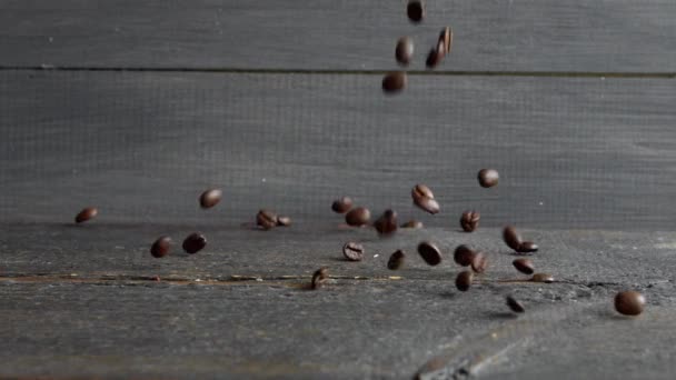 Fresh roasted coffee beans falls on a wooden table and bounces. Fresh roasted coffee in Arabica beans is prepared for grinding and making delicious coffee. — Stock Video