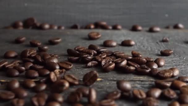 Biji kopi segar jatuh di atas meja kayu. Kopi panggang segar dalam biji Arabika disiapkan untuk menggiling dan membuat kopi yang lezat. — Stok Video