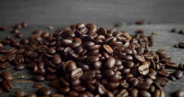 Grãos de café arábica torrados espalhados em uma mesa de madeira. Grãos de café frescos. Espresso, americano, doppio, cappuccino, latte. Robusta. Foco seletivo. — Vídeo de Stock