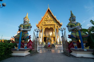 KOH SAMUI, THAILAND - 10 Ocak 2020: Wat Plai Laem Tapınağı 'ndaki tören salonunun önünde kırmızı elbiseli kadın duruyor.