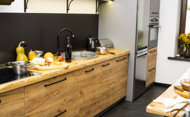 Mutfaktaki meşe mutfak atölyesinde lavabo, fırın ve yemek malzemeleri, şişe ve mutfak tesisleri var. Ahşap atölyenin pratik kullanımı. Modern iç mekan. Yemek pişirme.