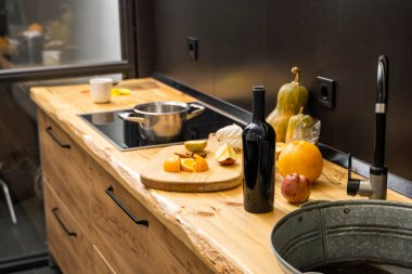 Mutfaktaki meşe mutfak atölyesinde lavabo, fırın ve yemek malzemeleri, şişe ve mutfak tesisleri var. Ahşap atölyenin pratik kullanımı. Modern iç mekan. Yemek pişirme.