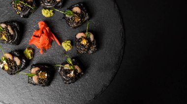 Suşi, siyah pirinç, yengeç eti, salatalık, avokado, tütsülenmiş somon balığı, kürek havyarı, masago, karides kokteyli ve kırmızı zencefil ve wasabi soslu yenilebilir altın yaprak..