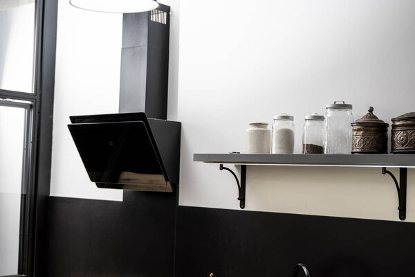 Черный стеклянный кухонный колпак на современной кухне с белыми стенами.