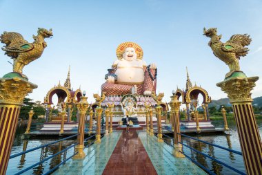 KOH SAMUI, THAILAND - 10 Ocak 2020: Kameralı bir adam Koh Samui Tayland 'daki Wat Plai Laem Tapınağı' ndaki dev renkli Buda heykelinin üzerinde duruyor..