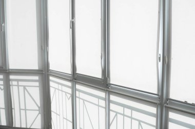 Oturma odasındaki bir balkondaki plastik pencerenin perdeleri beyaz kumaştan..