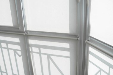 Oturma odasındaki bir balkondaki plastik pencerenin perdeleri beyaz kumaştan..