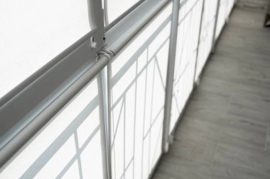 Oturma odasındaki bir balkondaki plastik pencerenin perdeleri beyaz kumaştan..