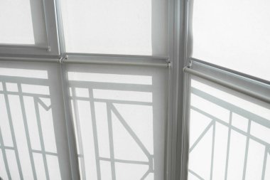 Oturma odasındaki bir balkondaki plastik pencerenin perdeleri beyaz kumaştan..