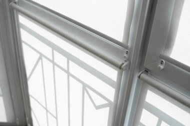 Oturma odasındaki bir balkondaki plastik pencerenin perdeleri beyaz kumaştan..