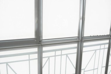 Oturma odasındaki bir balkondaki plastik pencerenin perdeleri beyaz kumaştan..