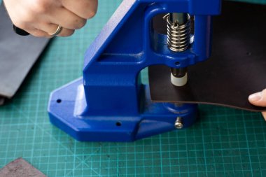 Zanaatkârlar cüzdan yapmak için deri mandalları kullanırlar. El Baskısı Baskı Makinesi deri atölyesinde zanaatkar tarafından kullanılıyor..