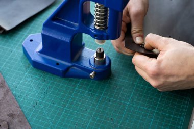 Zanaatkârlar cüzdan yapmak için deri mandalları kullanırlar. El Baskısı Baskı Makinesi deri atölyesinde zanaatkar tarafından kullanılıyor..