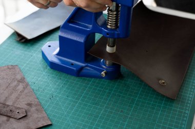 Zanaatkârlar cüzdan yapmak için deri mandalları kullanırlar. El Baskısı Baskı Makinesi deri atölyesinde zanaatkar tarafından kullanılıyor..