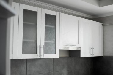 Modern minimalizm stili mutfak iç dekorasyonu tek renkli tonlarda. Mutfak kaputu ve lavabosu olan gri beyaz bir mutfak ve koyu gri bir tezgah. Chipboard 'dan modüler mutfak.
