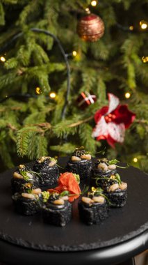 Siyah pirinçli suşi, yengeç eti, avokado, tütsülenmiş somon kreması, kürek havyarı, masago, karides kokteyli ve zencefilli altın yaprak..