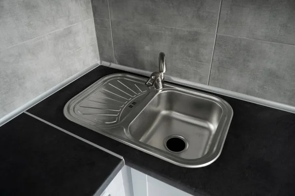 Évier de cuisine en acier inoxydable sur un plan de travail en granit gris foncé. évier et robinet d'eau dans la cuisine. — Photo