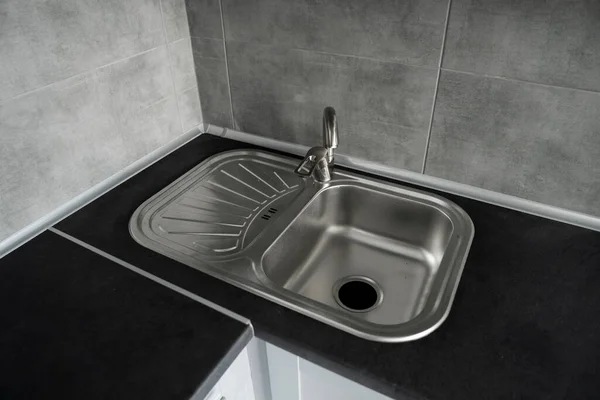 Fregadero de cocina de acero inoxidable en una encimera de granito gris oscuro. Lavabo de cocina y grifo de agua en la cocina. — Foto de Stock