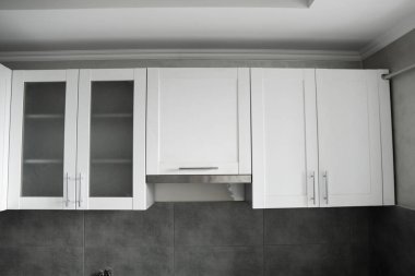 Modern minimalizm stili mutfak iç dekorasyonu tek renkli tonlarda. Mutfak kaputu ve lavabosu olan gri beyaz bir mutfak ve koyu gri bir tezgah. Chipboard 'dan modüler mutfak.