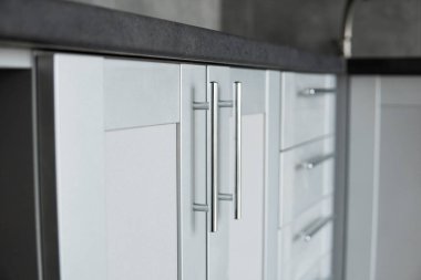 Modern minimalizm stili mutfak iç dekorasyonu tek renkli tonlarda. Mutfak kaputu ve lavabosu olan gri beyaz bir mutfak ve koyu gri bir tezgah. Chipboard 'dan modüler mutfak.
