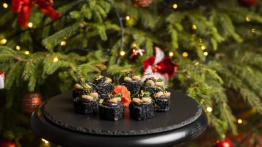 Siyah pirinçli suşi, yengeç eti, avokado, tütsülenmiş somon kreması, kürek havyarı, masago, karides kokteyli ve zencefilli altın yaprak..