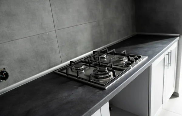 Metalowy piec gazowy ze stali nierdzewnej montowany na kuchni z ciemnoszarym blatem. — Zdjęcie stockowe