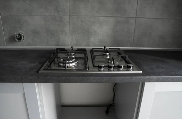 Fogão a gás de cozinha de metal cinza inoxidável instalado em uma cozinha com um tampo de mesa cinza escuro. — Fotografia de Stock