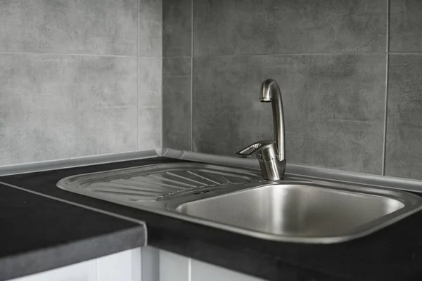 Küchenspüle aus Edelstahl auf einer dunkelgrauen Arbeitsplatte aus Granit. Spülbecken und Wasserhahn in der Küche. — Stockfoto