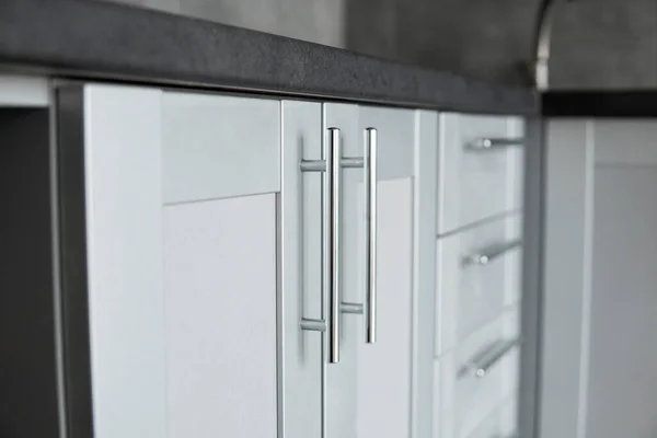 Modern minimalism style kitchen interior in monochrome tones. Custom kitchen with grey white facadesmdf and dark grey countertop with installed kitchen hood and sink. Modular kitchen from chipboard.